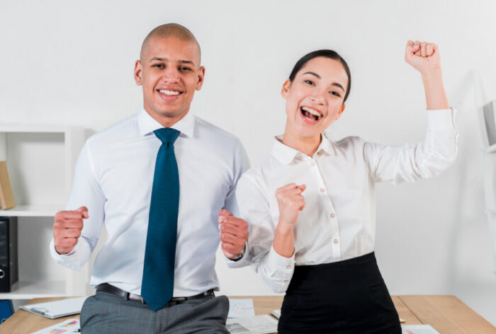 Excited overjoyed young business couple standing in front of table